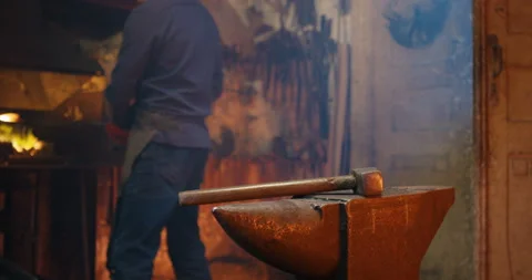 Caucasian blacksmith working in antique forge and forging while beating with Stock Footage 135331469