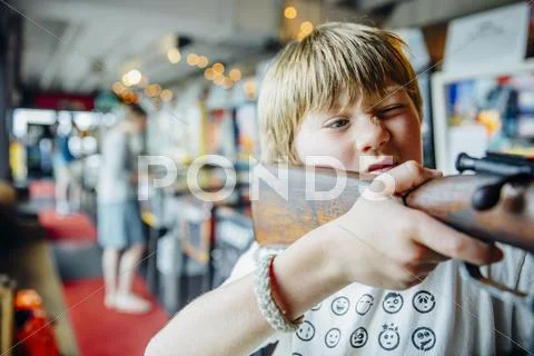 Caucasian boy aiming gun in arcade shooting game Stock Photos
