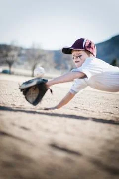 Caucasian boy catching baseball on field Stock Photos