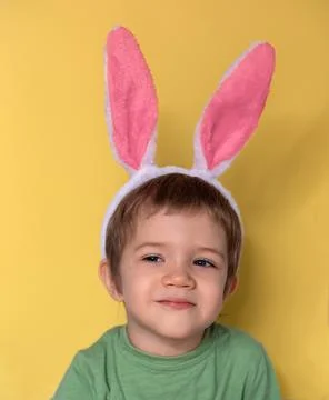 A caucasian boy with the Easter rabbit ears on yellow background Stock Photos