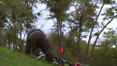 Caucasian boy falling down and carrying the bike on the hill while playing in a Stock Footage 152349590
