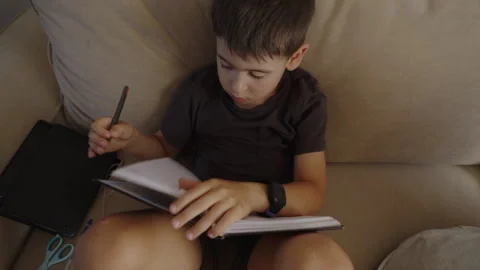 Caucasian boy learning to use pen and write on notebook, having fun doing Stock Footage 249736962