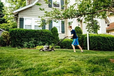 Caucasian boy mowing front lawn Stock Photos