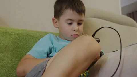 Caucasian boy plaing with a portable console on the couch. The excitement, the Stock Footage 251535902