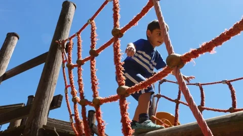 Caucasian boy playing at kid training playground, crossing a suspension bridge Stock Footage 134668904