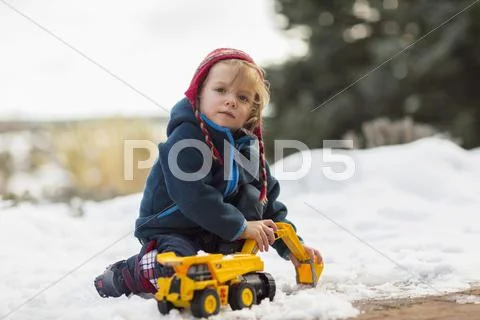 Caucasian Boy Playing With Truck In Snow