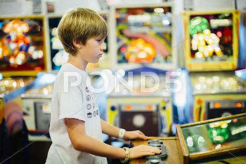 Caucasian boy playing video game in arcade Stock Photos