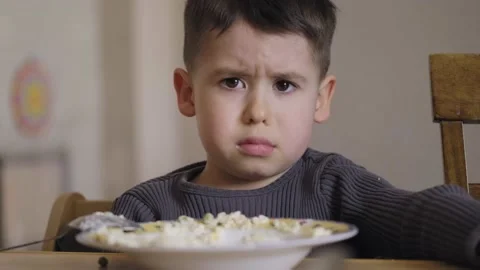 Caucasian boy refusing to eat his breakfast, sitting at table in the morning Stock Footage 198196594