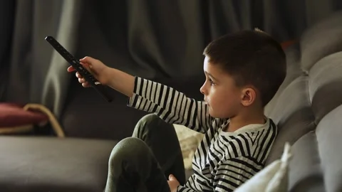 Caucasian boy sitting on sofa watching tv in living room. Side view of focused Stock Footage 302494920
