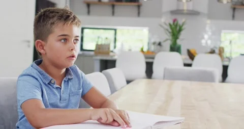 Caucasian boy sitting at table and reading braille, slow motion Stock Footage 337224048