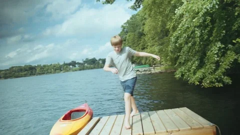 Caucasian boy spinning on floating dock at river Stockbeeldmateriaal 72325681