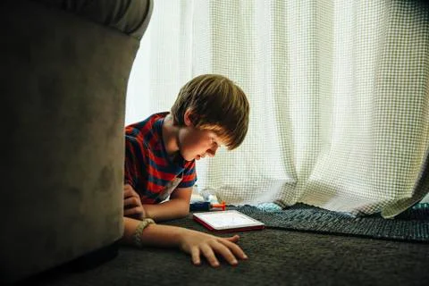 Caucasian boy using digital tablet in blanket fort Stockfoto's