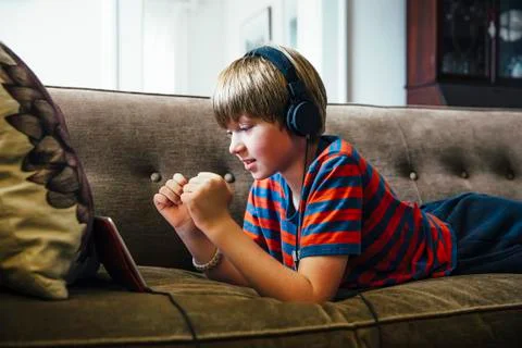 Caucasian boy using digital tablet on sofa Stockfoto's