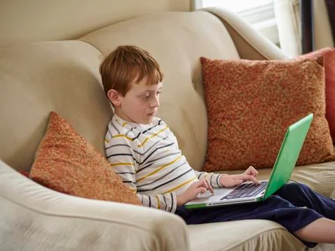 Caucasian boy using laptop on sofa 스톡 사진