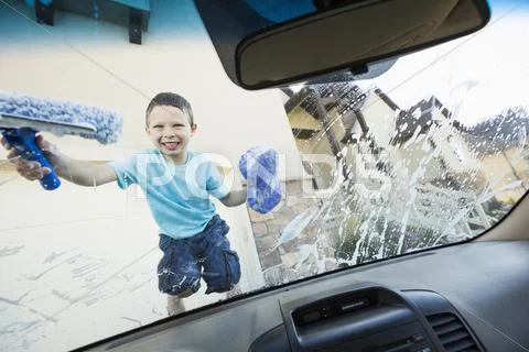 Caucasian boy washing car windshield Stock Photos