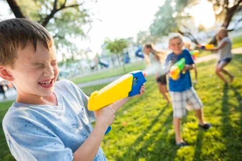 Caucasian boys and girls playing with squirt guns Stock Photos