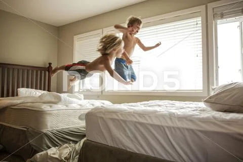 Caucasian Boys Jumping On Beds