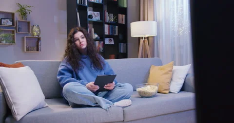 Caucasian brunette using digital tablet while sitting on sofa at home in evening Stock Footage 244143754