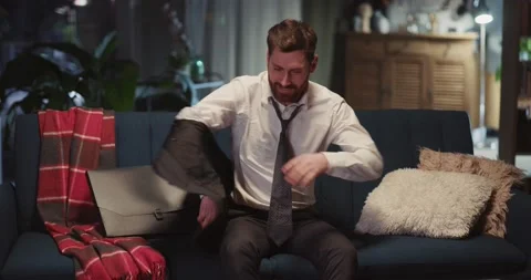 Caucasian business man going back home from office, taking off jacket sitting on Stock Footage 148160341