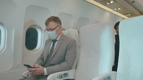 A Caucasian business man is using smart phone  in aircraft , wearing protecti Stock Footage 150652062