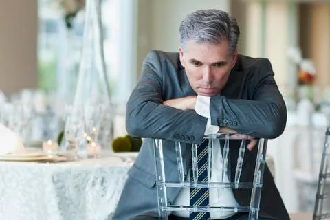 Caucasian businessman brooding in empty dining room Fotos de archivo