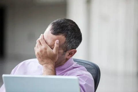 A Caucasian businessman pondering a problem while working on a laptop computer. Stock Photos