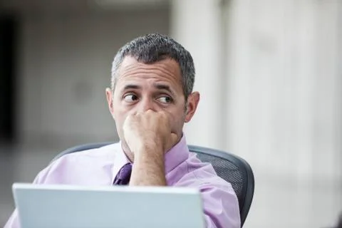 A Caucasian businessman pondering a problem while working on a laptop computer. Stock Photos