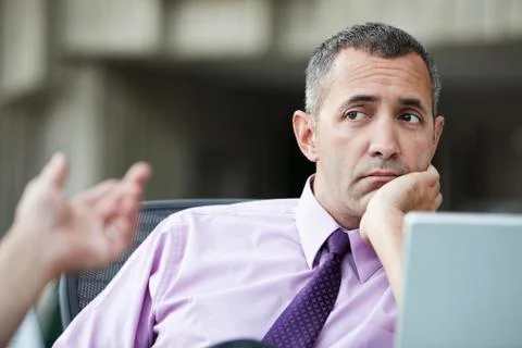 A Caucasian businessman pondering a problem while working on a laptop computer. Stock Photos