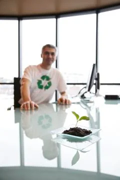 A caucasian businessman wearing a recycle t shirt while sitting at his office Stock Photos