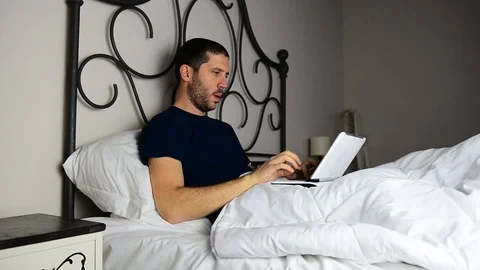 Caucasian businessman working on tablet while on bed, with various expressions 스톡 동영상 122311436