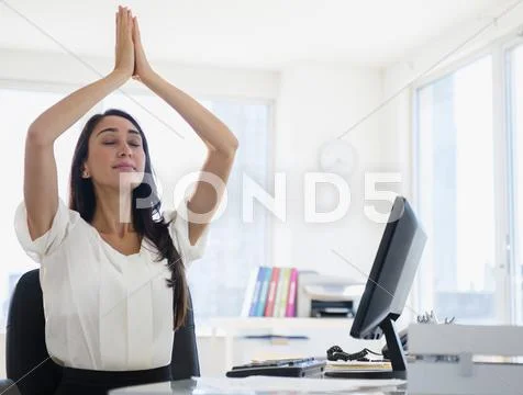 Caucasian businesswoman meditating at desk Stock Photos