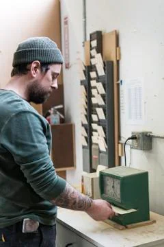 A Caucasian carpenter checking in with a time clock in a woodworking factory. Stock Photos