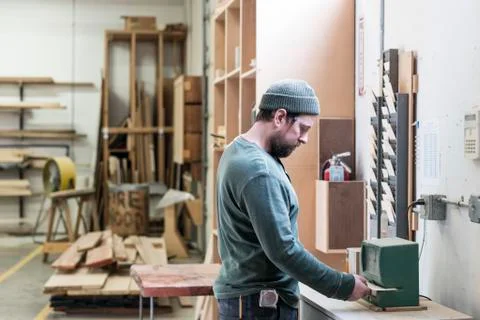 A Caucasian carpenter checking in with a time clock in a woodworking factory. Stock Photos