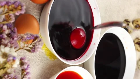 Caucasian child paints an Easter egg with a metal spoon and dips it into a white Stock Footage 147572161