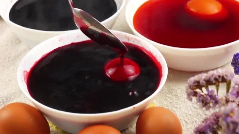 Caucasian child paints an Easter egg with a metal spoon and dips it into a white Video stock 147572198