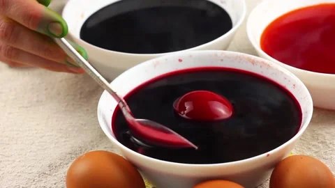 Caucasian child paints an Easter egg with a metal spoon and dips it into a white Stock Footage 147960621