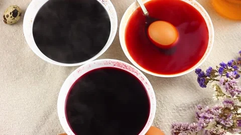 Caucasian child paints Easter eggs with a metal spoon dipped into a white bowl Stock Footage 145922235