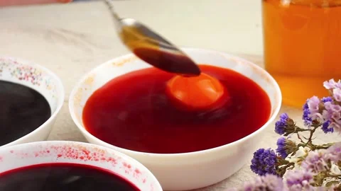 Caucasian child paints Easter eggs with a metal spoon dipped into a white bowl Video stock 148189534