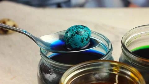 A Caucasian child paints a small Easter quail egg in a speck, dips it with a Stock Footage 147005608