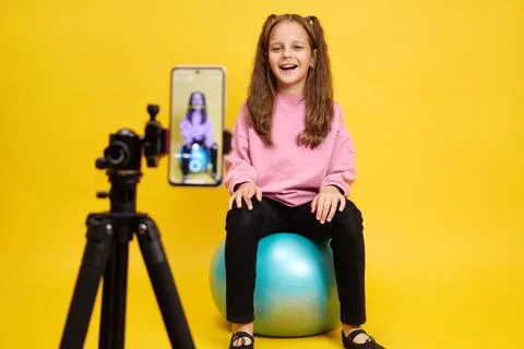 Caucasian child smiling while using technology to record fitness video with.. Stock Photos