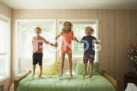 Caucasian Children Jumping On Bed