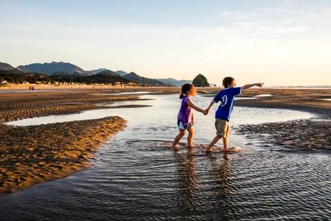 Caucasian children walking in tide pools on beach, Cannon Beach, Oregon, United Stock Photos
