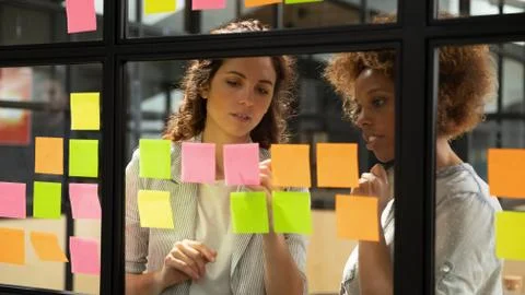 Caucasian coach explaining task african colleague writing on sticky notes Stock Photos