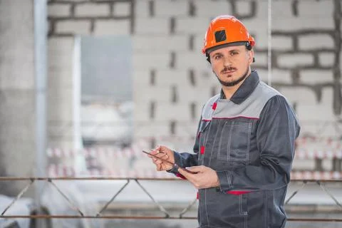 Caucasian construction foreman controlling building site with plan on digital Stock Photos
