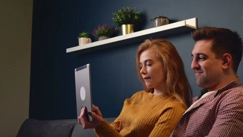 Caucasian couple are using a tablet on the couch smiling and spending together Stock Footage 147036372