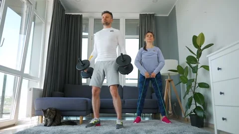 Caucasian couple doing strength training at home in cozy bright room, slow Stock Footage 201259199