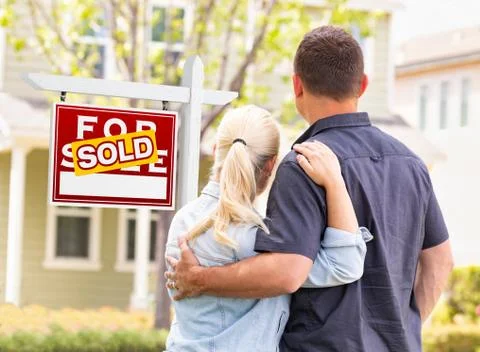 Caucasian Couple Facing Front of Sold Real Estate Sign and House. Stock Photos
