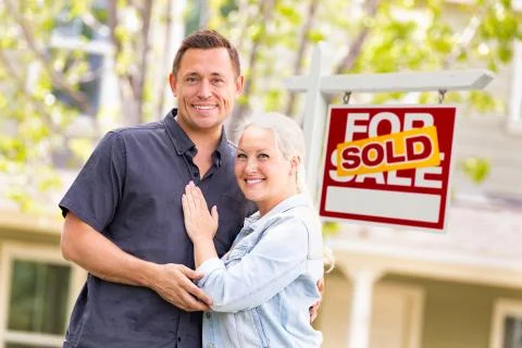 Caucasian Couple in Front of Sold Real Estate Sign and House. Stock Photos
