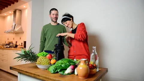 Caucasian couple laughing while making a fresh juice in the kitchen 스톡 동영상 122300971
