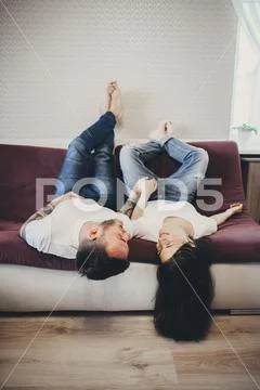 Caucasian Couple Laying Upside-Down On Sofa